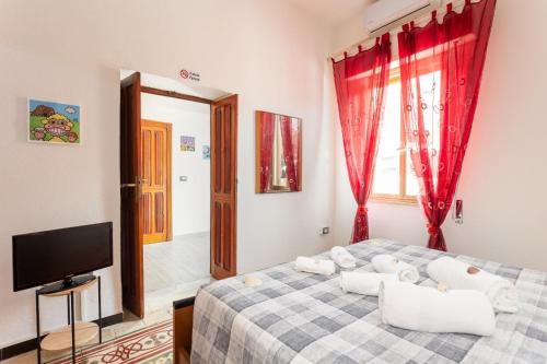 a bedroom with a bed with red curtains and a tv at La Campidanese IUN R3640 in Càbras