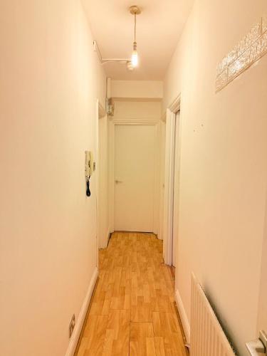 a hallway with a white door and a wooden floor at Spacious Room with Double and semi double bed, Shared bathroom,10 minutes to Aldgate East station, near Central London, for 4 ppl in London