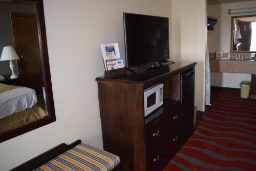 a hotel room with a television on a dresser at Travelodge Inn & Suites by Wyndham Norman in Norman
