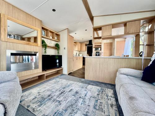 ein Wohnzimmer mit Sofa und Fernseher in der Unterkunft The Windermere- Luxury Caravan Retreat by the Sea in Devon in Burgh Island