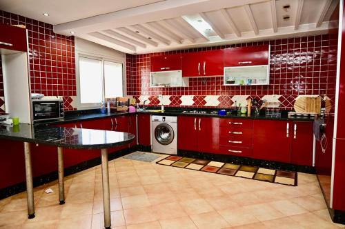 una cucina con armadi rossi e una lavatrice di Harhoura, plage, piscine et confortable a El Harhoura