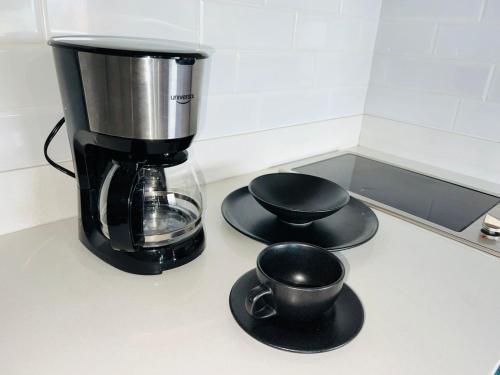 a coffee maker and cups on a counter at Hotel Living 35 Suites in Medellín