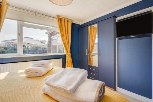 1 dormitorio con paredes azules y 1 cama con toallas. en Broadway Bungalow, en Heacham