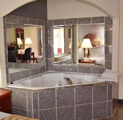a bath tub in a hotel room with a mirror at Travelodge Inn & Suites by Wyndham Norman in Norman