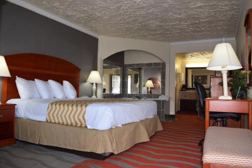 a hotel room with a large bed and a desk at Travelodge Inn & Suites by Wyndham Norman in Norman