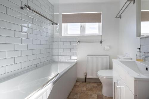 a white bathroom with a sink and a toilet at Scribblers Cottage in Woodbridge