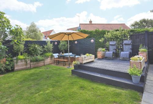 a backyard with a wooden deck with an umbrella at Cobblers in Theberton