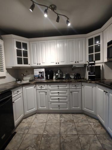 a white kitchen with white cabinets and black appliances at Royal Rays in Bowmanville