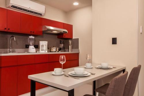 a kitchen with red cabinets and a table with plates and wine glasses at City Express Plus by Marriott Cabo San Lucas in Cabo San Lucas