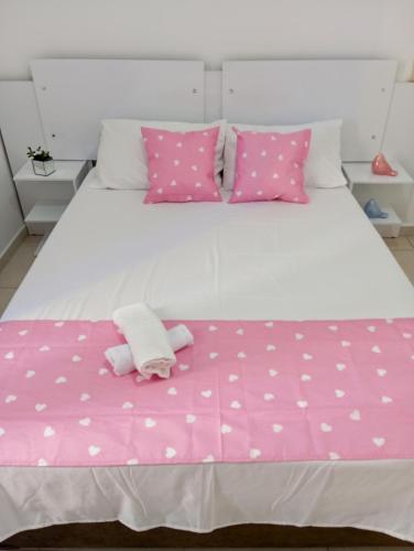 a white bed with pink polka dot sheets and pillows at Apto mobiliado no edificio saveiro com garagem in São José dos Campos