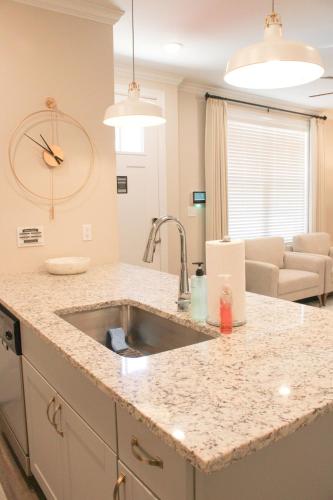 a kitchen counter with a sink and a living room at Chic Townhome near LA Tech in Ruston