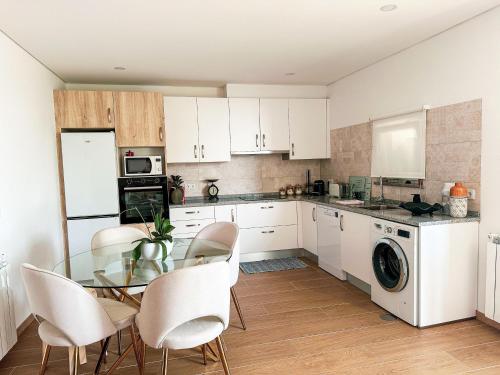 a kitchen with a glass table and white cabinets at Le refuge in Tondela
