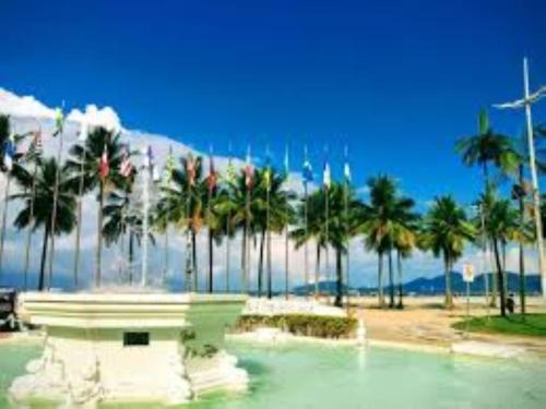 a fountain in the water with palm trees on a beach at Santos Prime Stay in Santos