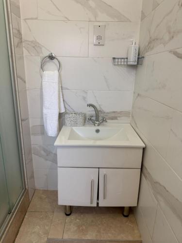 un bagno bianco con lavandino e doccia di Wilo Residence a Victoria Falls