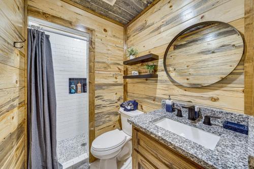 a bathroom with a toilet and a sink and a mirror at Hike, Fish and Unwind Cabin with Yard in Broken Bow! in Broken Bow