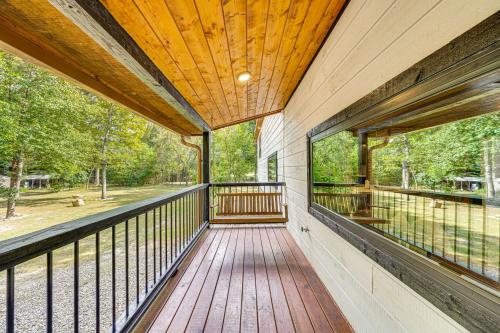 a large balcony with a wooden deck with windows at Hike, Fish and Unwind Cabin with Yard in Broken Bow! in Broken Bow