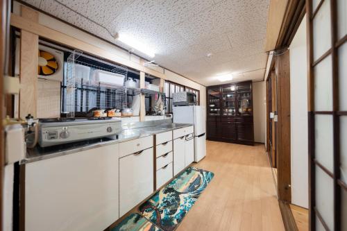 a kitchen with white cabinets and a refrigerator at Former Yoshidaya Hikonana Residence, a Registered Tangible Cultural Property 倉敷の宿 国登録有形文化財 旧吉田彦七邸 一棟貸切 1日1組限定 特別な体験 日本の伝統建築で過ごす非日常を in Kurashiki