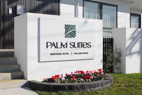 a sign forpain surfaces outside a building with flowers at Palm Suites - Auckland in Auckland