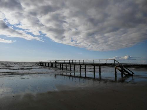 a pier on the beach with a cloudy sky at Secluded Retreat in Blavand - By Traum Ferienwohnungen in Blåvand