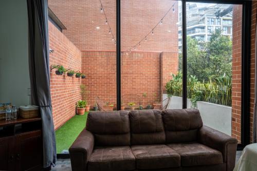 a brown couch in a living room with a large window at Cómodo loft en centro de zona 4 in Guatemala