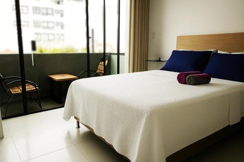 a bedroom with a large white bed with blue pillows at 2C - Confort y ubicación en Sirari, cerca Ventura Mall in Santa Cruz de la Sierra