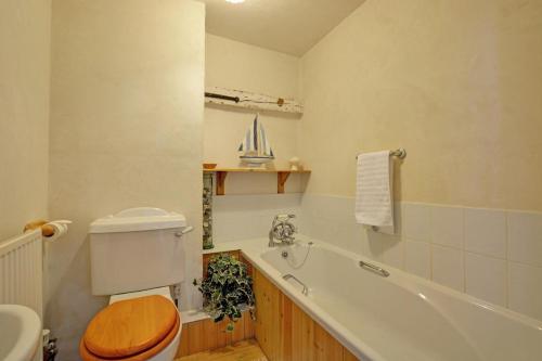 a bathroom with a toilet and a tub and a sink at The Old Coach House in Cawston