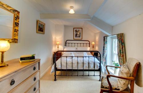 a bedroom with a bed and a chair and a dresser at Mundles Cottage in Whittingham