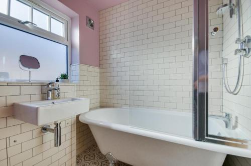 Un baño blanco con bañera y lavabo. en Oaklea, en Burnham Market