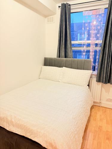 a bedroom with a white bed with a window at The settle Nest- Bright Semi Double room for 2ppl with shared bathroom-10 minutes to Aldgate East Station, close to central London, in London