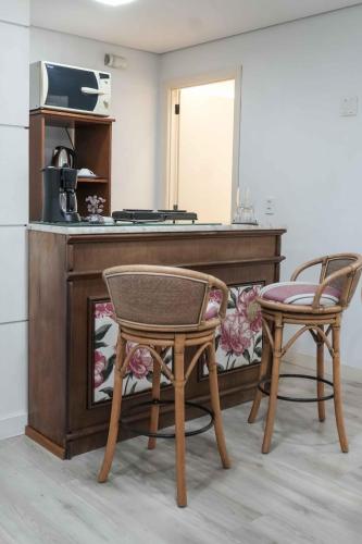 a kitchen with a counter with two chairs and a table at G1 Fashion ap 102 in Caxias do Sul