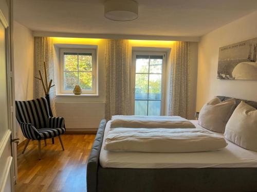 een slaapkamer met een bed, een stoel en ramen bij Rosenberger I und II in Hopfgarten im Brixental