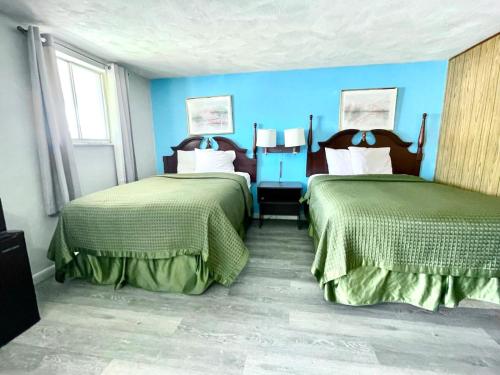 Dos camas en una habitación con paredes azules. en Travelers Inn Olney, en Olney