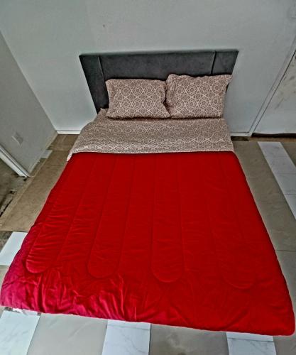 a bed with a red comforter and two pillows at Cosi Room Near Austin in Pflugerville