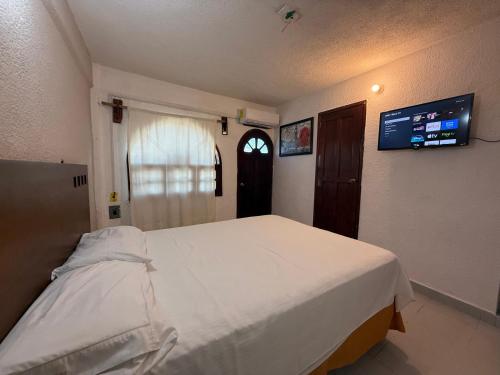 a bedroom with a white bed and a tv on the wall at Hotel Colonial in Escárcega