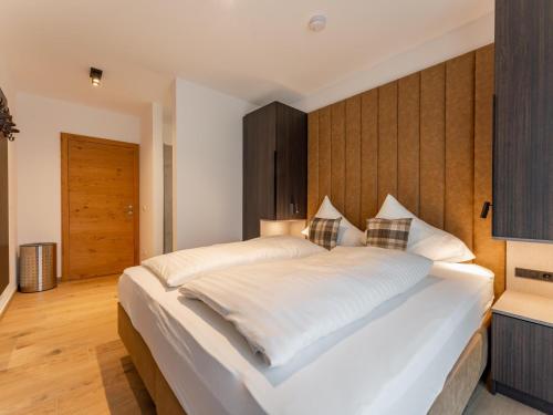 a bedroom with a large white bed with a wooden headboard at Grebenzen Lodge Edelblick in Sankt Lambrecht
