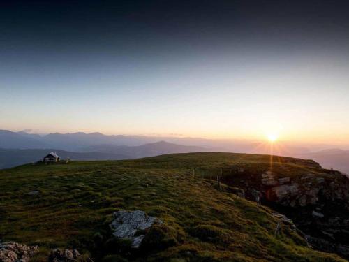 a house on the top of a hill with the sunset at Grebenzen Lodge Edelblick in Sankt Lambrecht