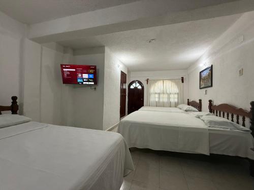 a bedroom with two beds and a tv on the wall at Hotel Colonial in Escárcega