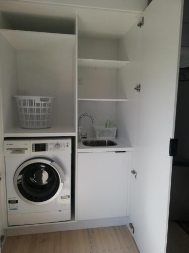 a laundry room with a washing machine and a sink at Beach Cottage in Mount Maunganui