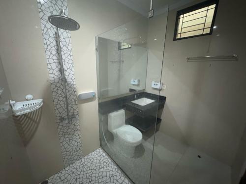 a bathroom with a toilet and a glass shower at Elbara Guest House Syariah in Banjarbaru