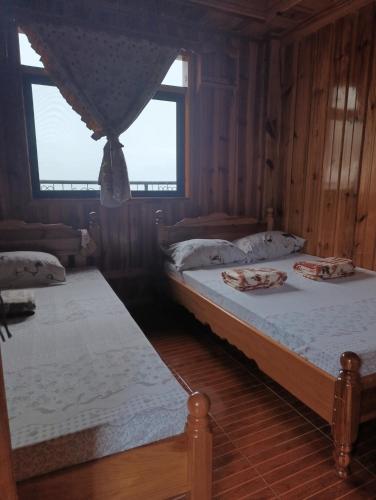 two beds in a room with wooden walls at Sea of clouds view inn in Sagada