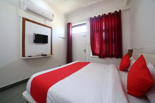 a bedroom with a bed with red pillows and a mirror at Hotel O Rawat in Ajmer