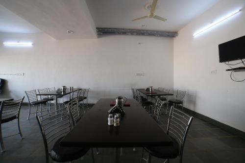 a dining room with tables and chairs and a flat screen tv at Hotel O Rawat in Ajmer