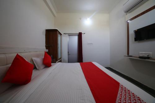 a bedroom with a bed with red pillows at Hotel O Rawat in Ajmer