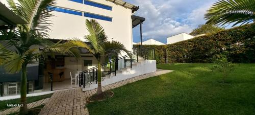 a white house with palm trees in the yard at Hotel y Cabañas Parinzzi in Guatapé