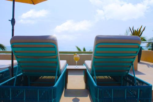 two chairs and a table with a drink on a balcony at ÚNICO LA PUNTA HOTEL BOUTIQUE Beach club in Brisas de Zicatela