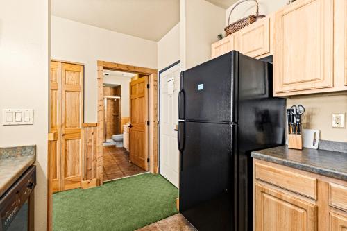 a kitchen with a black refrigerator and wooden cabinets at Amazing Superior Lake View Condo and Heated Pools in Two Harbors