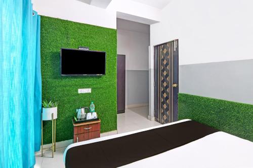 a bedroom with a green wall with a tv at OYO 82026 BANGUR INN in Nager Bazaar
