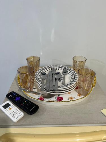a table with a plate and glasses and a remote control at Quarto privado próximo ao centro in Manaus
