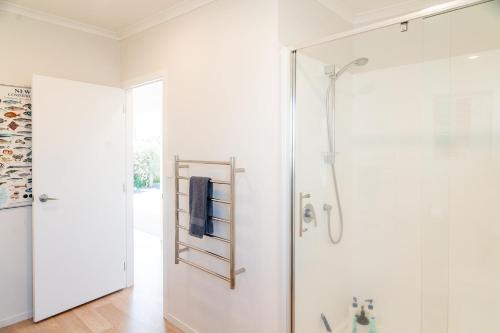 a bathroom with a shower with a glass door at Reel retreat - sunny with views! in Waihi Beach