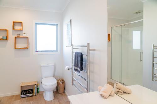 a bathroom with a toilet and a glass shower at Reel retreat - sunny with views! in Waihi Beach